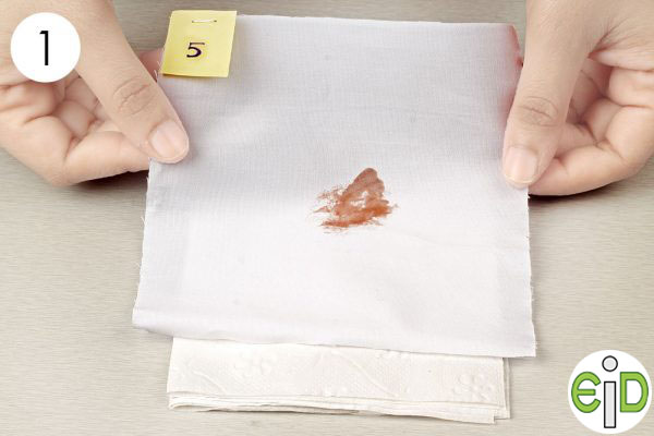temizlik için tuvalet ispirtosu kullanmak için lekeli kumaşı birkaç kağıt havlu üzerine yerleştirin